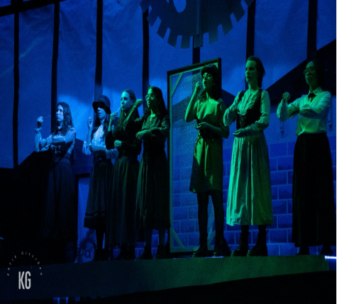 “Radium Girls” cast members perform under atmospheric green stage lighting and an elaborate glowing brick wall backdrop, thanks to the shows talented stage crew, in the high school auditorium on Nov. 14, 2022. 