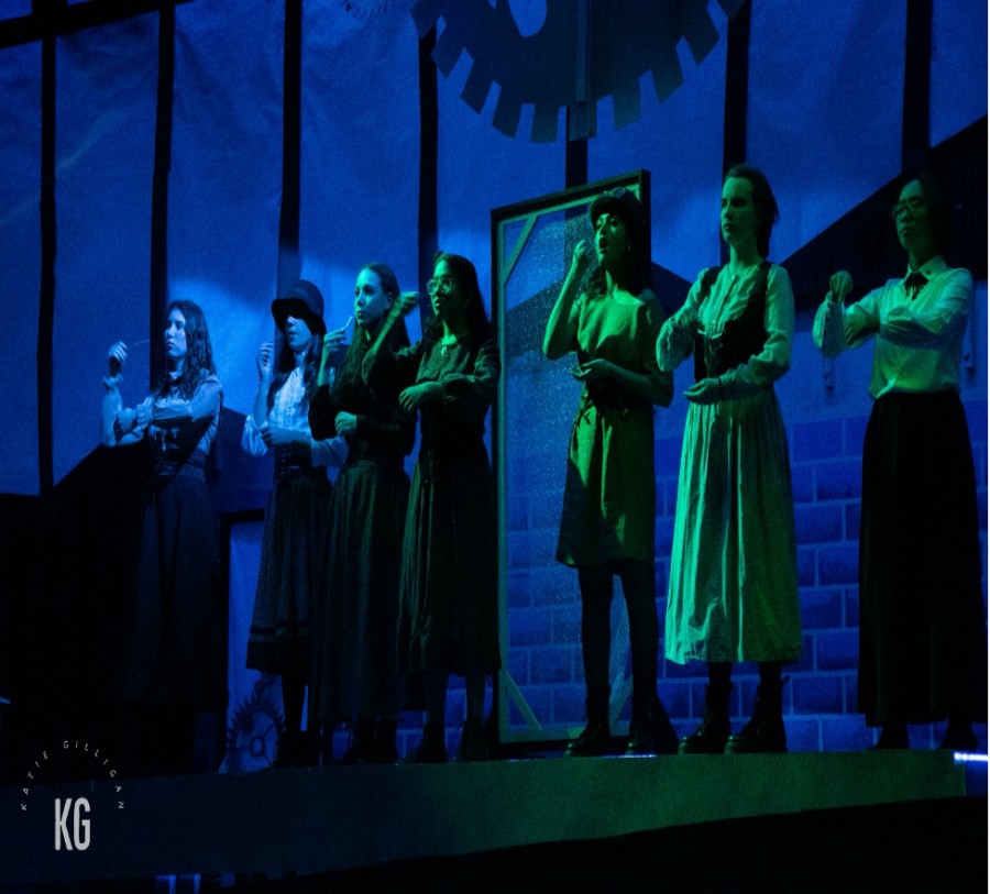 “Radium Girls” cast members perform under atmospheric green stage lighting and an elaborate glowing brick wall backdrop, thanks to the shows talented stage crew, in the high school auditorium on Nov. 14, 2022. 