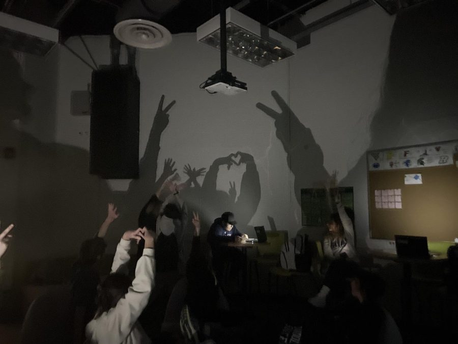 High school students make shadow puppets on the wall of a classroom while awaiting instructions from administrators during a power outage that affected all of Randolph Township, leading to an early dismissal for all students, on Jan. 12, 2023. 