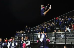 Freshman varsity cheerleader Cate Glauberg is thrown into the air during a football game this season.