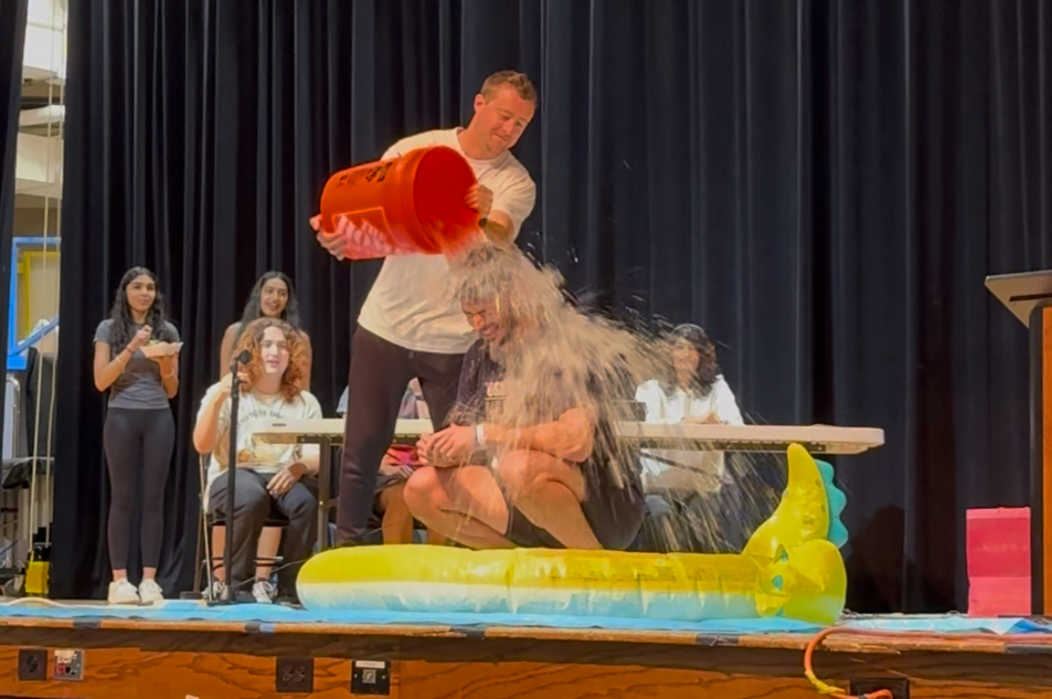 Social Studies Teacher Jacob Torsiello takes the Ice Bucket Challenge, with an assist from colleague Erik Novack, to help raise money for child cancer research in the high school auditorium on Friday, May 2, 2025. 