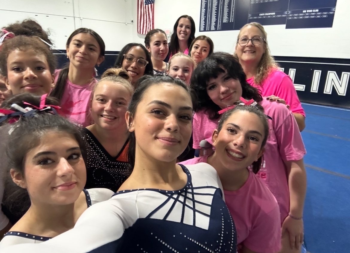 The Randolph Gymnastics team smiles for a selfie after an October meet, proudly wearing pink to support Breast Cancer Awareness Month. 