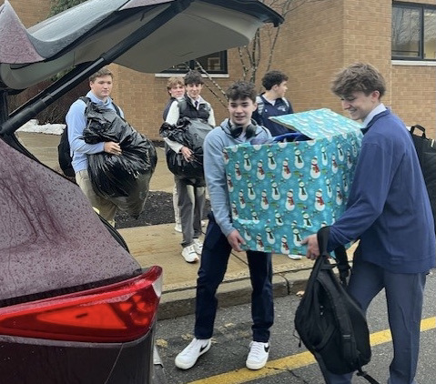 Members of the Boys Basketball team load donated coats into a car for distribution. 