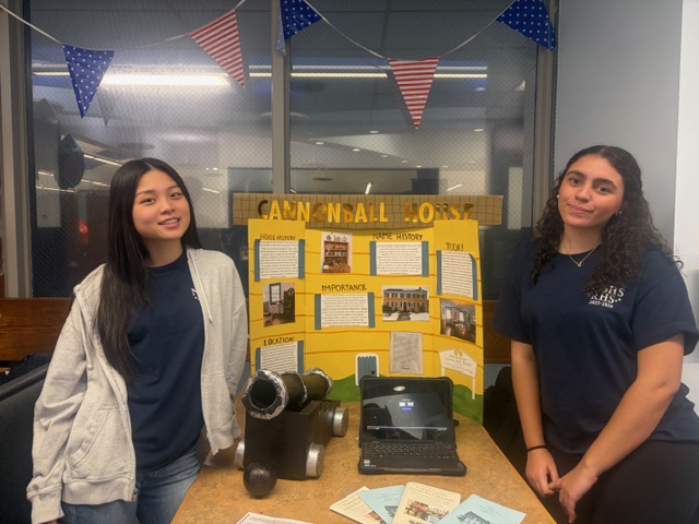 Stephanie Weng (left) and Valeria Reynaldo present their trifold on the Cannon Ball House at Red, White, & Jersey at RHS on March 5, 2026. 