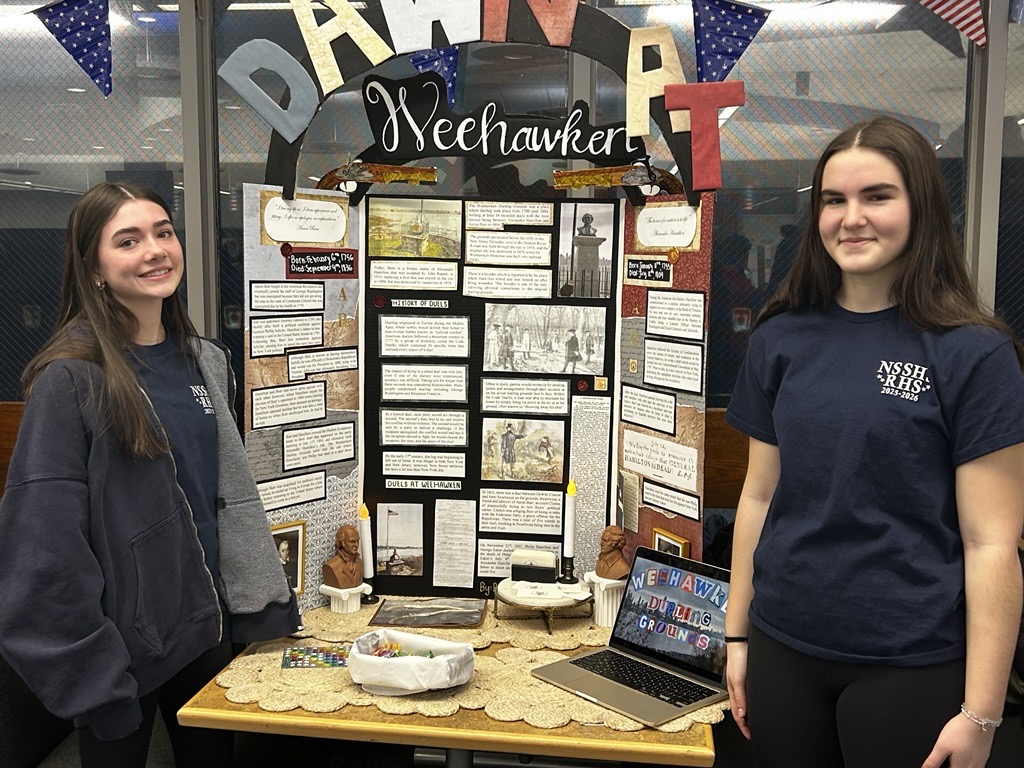 Finley Rantas (left) and Brielle Nuzzo display their trifold on the Dawn at Weehawken at Red, White, and Jersey at RHS on March 5, 2026.   The team took third place for their display. 