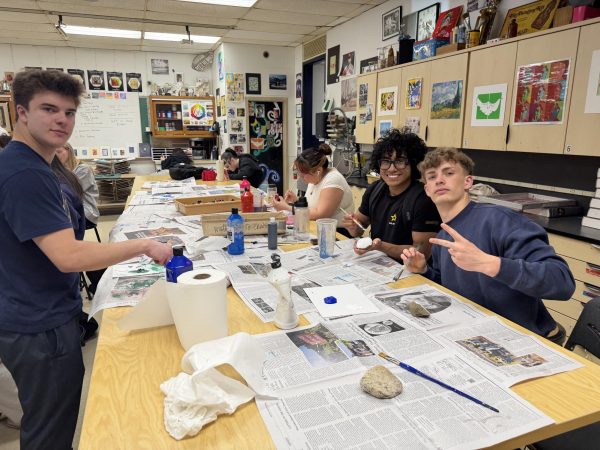 Clockwise, from left: Seniors Ryan Thomas, David Canelo and Connor Decker paint rocks to decorate the front of the high school during Wellness Week on Tuesday April 21, 2026.