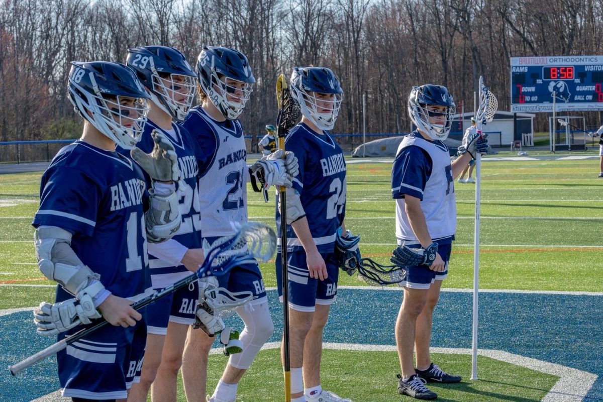 Varsity Boys Lacrosse players (from left) Mark Manolis, Cole Miller, Justin Novak, Ryan Barnett and Nick Cirella meet at the middle with the opposing team before the start of a recent game during the 2025-26 season.